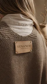 Ruana de hilo de algodón color beige, de diseño amplio y liviano con terminaciones tejidas en los bordes y costados abiertos.