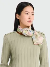 Pañuelo de seda Longchamp con estampado inspirado en viajes, que presenta motivos de sellos postales, cartas y matasellos en tonos multicolores sobre fondo claro con bordes verdes.