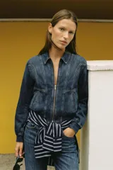 Campera bomber de denim en color gris oscuro con efecto lavado, cuello camisero, cierre frontal de cremallera metálica, bolsillos laterales ribeteados y terminaciones elásticas en puños y cintura.