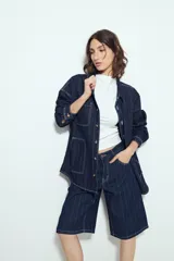 Bermuda de denim en color azul oscuro con diseño de rayas verticales blancas. Presenta un corte holgado, tiro medio y cierre frontal con botón y cremallera.