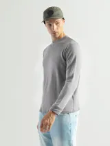 Remera de manga larga con cuello redondo, confeccionada en tejido de algodón tipo mini piqué. Presenta un diseño versátil con puños elásticos en las mangas, ideal para usar como prenda base o como buzo ligero.