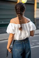 Blusa blanca con escote elástico que permite usarla con hombros descubiertos o más alta.