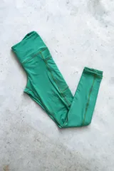 Calza deportiva larga color verde con costuras reforzadas en marrón y bolsillos laterales.