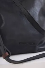Cartera de cuero negro con textura granulada, cuenta con una correa ajustable y el logo de la marca By Florencia grabado en el frente.