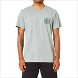 Remera Katin manga corta color verde claro, con cuello redondo y pequeño estampado circular en el pecho con texto y diseño de flor.