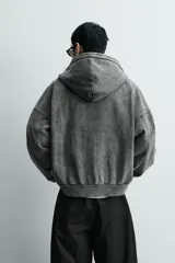 Sudadera con capucha y cierre de cremallera frontal, color negro con efecto lavado (acid wash). Presenta un corte relajado (relaxed fit) y bolsillos tipo canguro frontales.