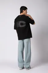 Remerón de corte oversized confeccionado en tejido rústico, con cuello redondo y mangas cortas. Presenta un diseño minimalista con una pequeña estampa frontal centrada en el pecho.