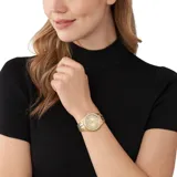 Reloj de pulsera Michael Kors modelo Harlowe, con caja y malla de acero inoxidable en tono dorado. Presenta una esfera dorada con acabado sunray, números romanos y un bisel decorado con cristales brillantes.