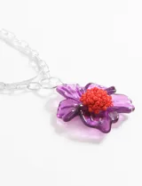 Collar con cadena plateada de eslabones grandes y dije de flor de plástico transparente color violeta con centro de mostacillas rojas.