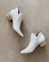 Botín corto color beige con textura símil piel de cocodrilo, taco de madera y laterales con corte en V.