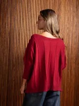 Buzo de punto color crema con escote bote, mangas tres cuartos y detalle de trenzas verticales en el frente.