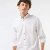 Camisa de lino mezclado color blanco, con cuello con botones, manga larga y botones frontales en contraste de efecto madera.