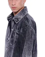 Camisa de denim negra con efecto lavado, corte recto, mangas cortas y bolsillo en el pecho.