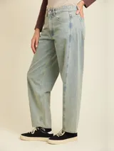 Jean de denim en corte balloon fit, con tiro medio y lavado claro. Presenta costuras laterales curvadas que definen su silueta amplia y relajada.