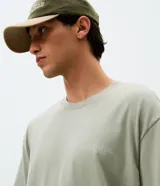 Remera de algodón con corte relajado, cuello redondo y mangas cortas. Presenta una estampa trasera con ilustración de mosquetones y el texto Essential, junto con una estampa frontal discreta.