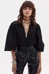 Camisa negra de encaje de algodón con cuello camisero clásico, mangas largas abullonadas con puños elásticos y cierre frontal con botones de nácar.