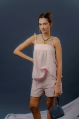Conjunto de dos piezas confeccionado en lino color rosado, compuesto por una musculosa de corte amplio con breteles de lazo regulables y un short con elástico en la cintura y bolsillos delanteros redondeados.