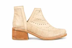 Botín de cuero blanco con textura de crocco y charol, diseño con calados circulares y aberturas laterales en forma de V. Cuenta con taco foliado de madera y vira cosida.