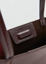 Bolso tipo shopper de diseño estructurado en color bordó con acabado brillante y efecto arrugado. Cuenta con doble asa larga para llevar al hombro y costuras verticales decorativas en el frente.