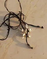 Collar tipo gargantilla con dije de flor metálica de acabado brillante, suspendido de un cordón doble de seda natural teñido a mano en color rojo.