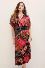 Vestido midi de viscosa con estampado floral en tonos rojos, naranjas y negros sobre base oscura. Cuenta con mangas cortas amplias, escote en V con cuello tipo camisero y cierre frontal de botones.