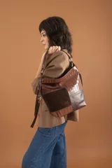 Bolso tipo hobo de cuero marrón con textura croco y cuero liso. Tiene dos asas cortas y una correa larga extensible y desmontable. El interior está forrado en tela y cuenta con un bolsillo con cierre y un bolsillo para celular. En el exterior tiene un bolsillo trasero con cierre.