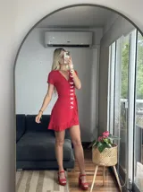 Vestido corto rojo con escote cruzado, mangas cortas y falda con volados. Se ajusta con lazo lateral tipo pareo.