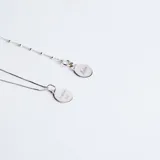 Conjunto de cadena fina y medalla circular de plata 925, con grabado lineal de figuras infantiles en el frente.