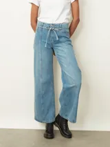 Jean de corte wide leg en color azul claro, con cintura elástica ajustable mediante cordón y costuras verticales decorativas en el frente.