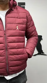 Campera puffer de nylon color bordó con capucha y cierre frontal.