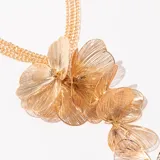 Collar dorado con cadena de múltiples hilos y colgante de flores de alambre.