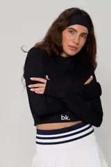Top deportivo negro de manga larga, confeccionado en tejido acanalado, con cuello alto y cierre frontal parcial. Presenta un diseño ajustado tipo crop top con el logo 'bk.' estampado en el frente.