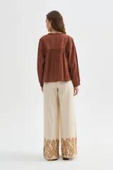Pantalon ancho de algodón en color beige con detalle de bordado decorativo en el ruedo.