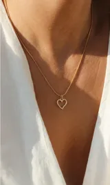 Collar de acero dorado con cadena fina tipo serpiente y dije de corazón calado con incrustaciones de circonias.