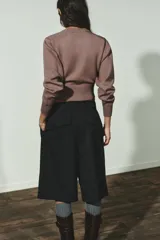 Jersey de punto liso con diseño cropped, cuello redondo y manga larga. Presenta acabados en rib en cuello, puños y bajo.