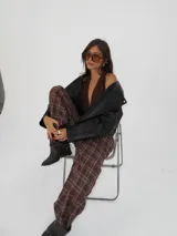 Pantalón de corte ancho con cintura elástica y bolsillos laterales, estampado a cuadros en tonos marrones.