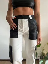 Pantalón de cuero sintético blanco y negro, de corte recto, con bolsillos laterales y traseros.