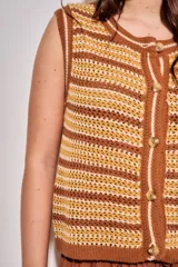 Chaleco de punto sin mangas con diseño de rayas horizontales en tonos marrones, amarillos y beige. Presenta un cierre frontal con botones y cuello redondo con terminación acanalada.