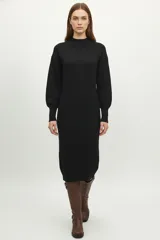 Vestido midi negro de tejido de punto, corte ajustado al cuerpo, con cuello polera y mangas largas abullonadas.