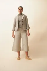 Chaqueta de corte recto color gris claro, con cuello, solapa y bolsillos ojal. Forro solo en las mangas y terminaciones envivadas. Esquinas redondeadas y mangas con corte en puño que permiten transformarla en manga 3/4. Más larga en la espalda que en la delantera. Abrochadura con dos botones.