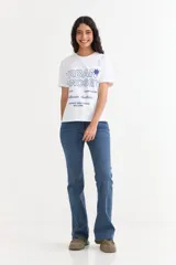 Remera de manga corta color beige, con estampa frontal en tono azul con la leyenda "New York 1990", de corte holgado y diseño casual.