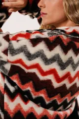 Tapado largo de lana con estampado zigzag horizontal en tonos rojo, negro, blanco y gris. De manga larga y abotonado.