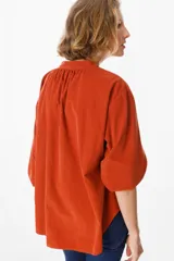 Camisa de pana color verde oliva, con cuello mao, cierre frontal de botones y mangas largas abullonadas con puños elásticos.