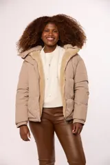 Campera reversible para mujer con diseño acolchado de nylon en un lado y corderito sintético en el otro. Cuenta con capucha, cierre frontal y mangas largas.