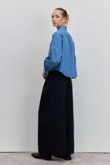 Camisa de corte oversize con diseño de rayas verticales en tonos azul y blanco, cuello clásico, cierre frontal con botones y mangas largas con puños abotonados.