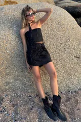 Conjunto de dos piezas compuesto por un top strapless y una falda corta tipo pareo, confeccionados en una combinación de lino y tul con bordado de pequeñas perlas metálicas en tono oro viejo.