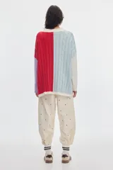 Buzo de punto oversized con diseño colorblock en celeste, rojo, blanco y lila. Presenta cuello redondo, tejido de ochos, pequeños tajos laterales y parche de la marca en la manga.