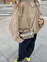 Chaqueta tipo bomber de calce holgado, confeccionada en gamuza color beige. Presenta cuello camisero, cierre frontal, mangas amplias y largo a la cintura.