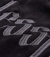 Remera oversize de tejido tipo gamuza sintética negra, con cuello redondo, manga corta y bordado de cruz gótica en el pecho.