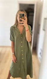 Vestido camisero midi color verde oliva, con cuello clásico, mangas cortas con trabillas y botones dorados, y cierre frontal con botones dorados.